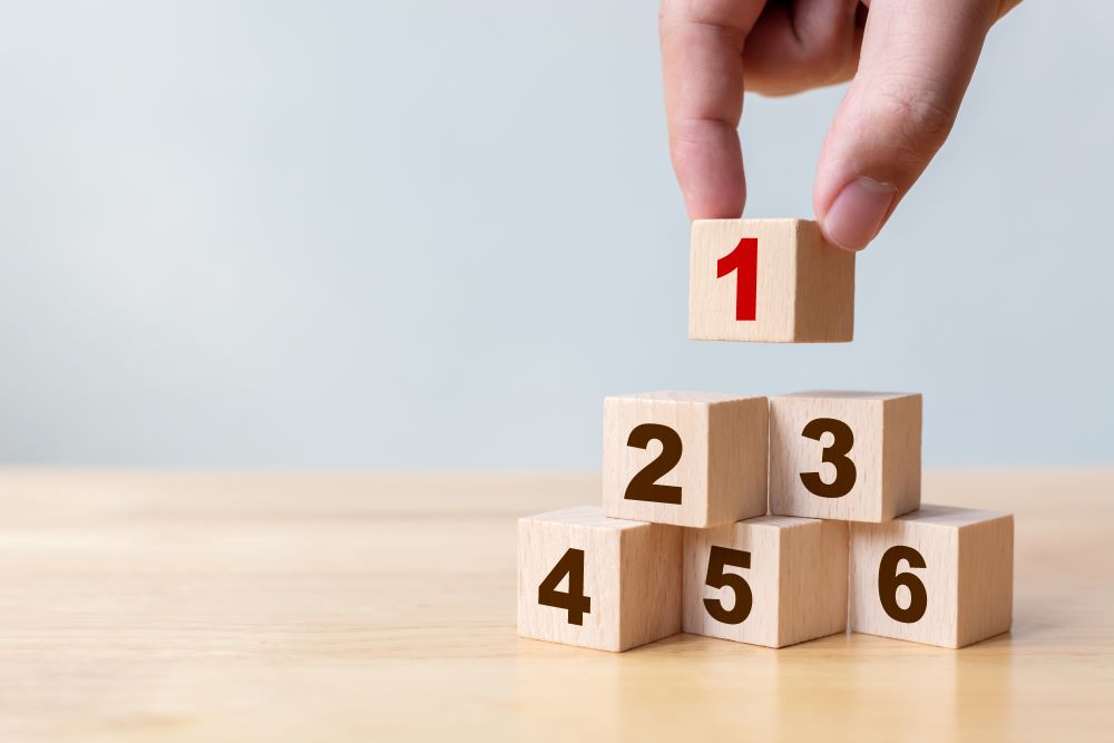 Hand arranging wood block stacking as step stair with number